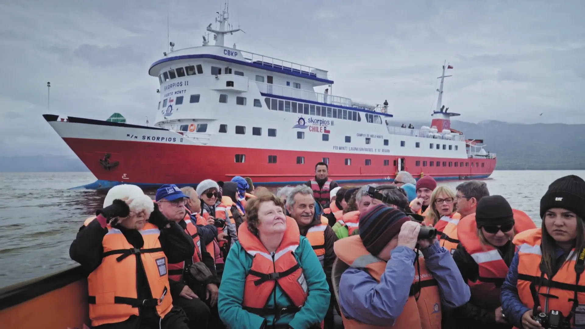 Grupo de pasajeros en un bote frente al Skorpios II